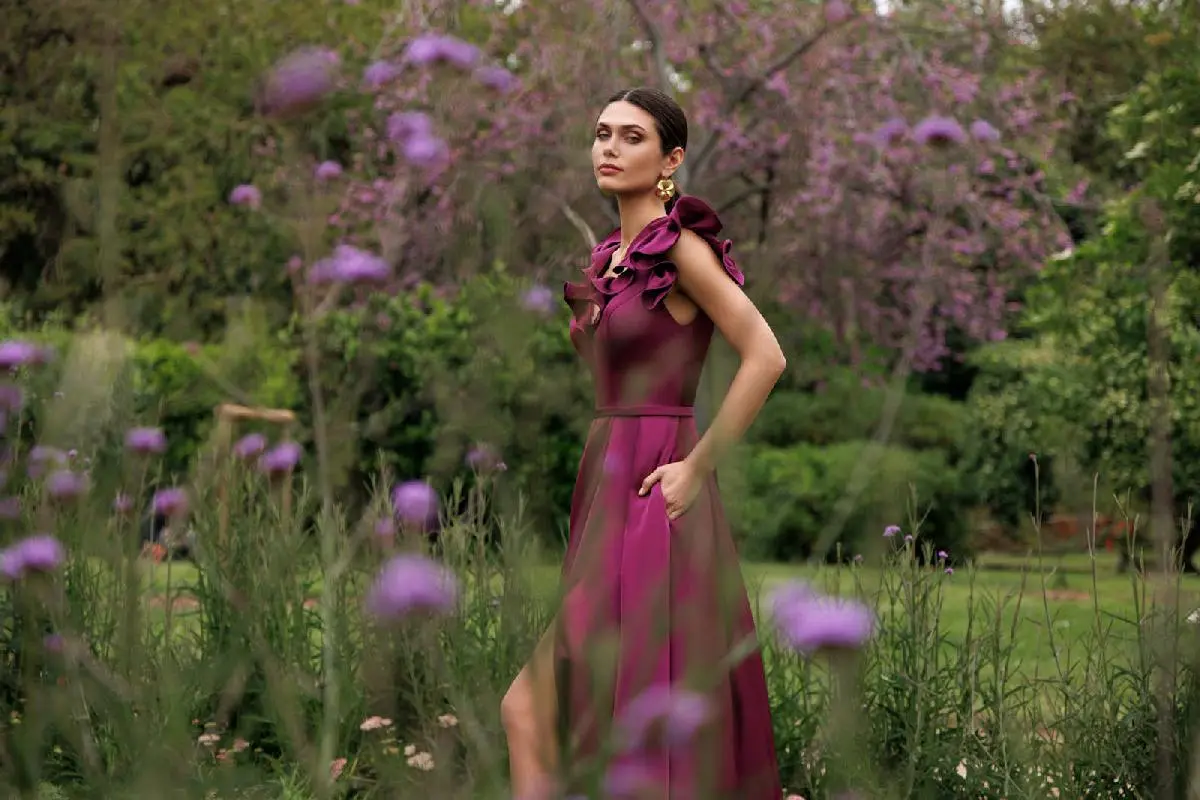 Robe de soirée prune avec volants aux épaules dans un jardin fleuri - Aime Comme Mariage Beynost