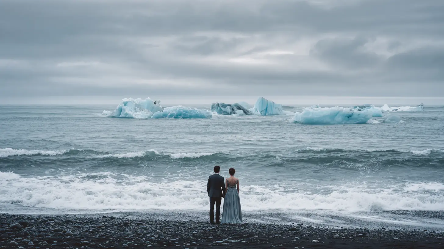 Couple de mariés en tenue de cérémonie sur une plage de sable noir islandaise, icebergs bleutés visibles au loin dans la lagune glaciaire, ciel nuageux et lumineux, ambiance intimiste et poétique, style photographique éditorial, format 16:9